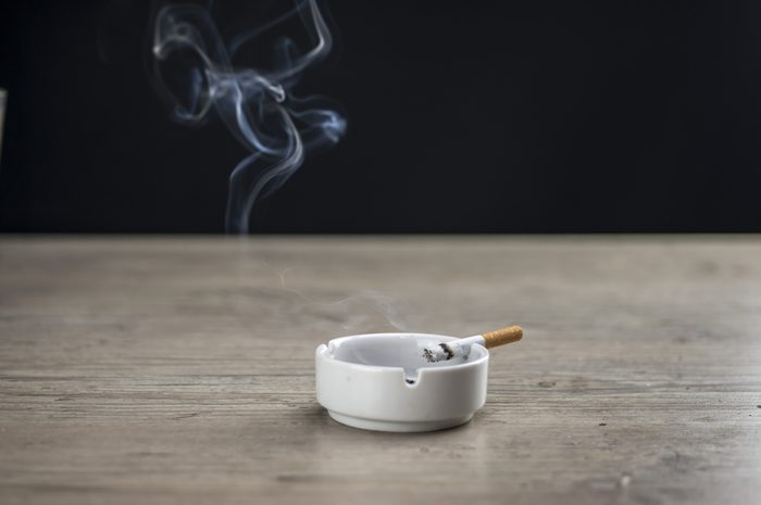 Lit cigarette burning in ashtray close up