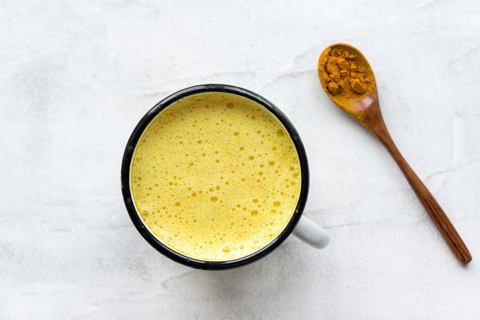 mug of turmeric drink and spoonful of turmeric powder