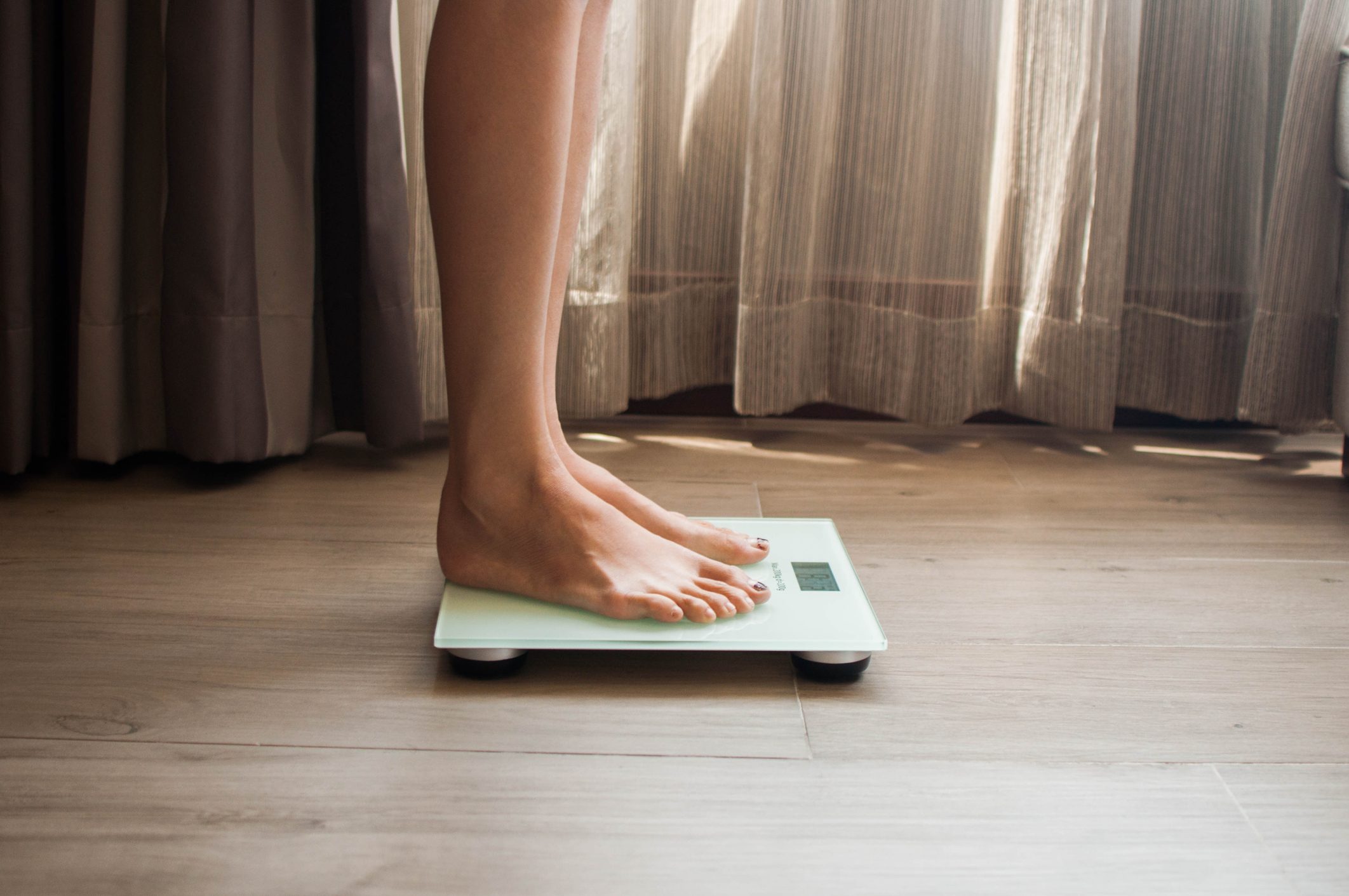 woman standing on scale close up of legs and feet