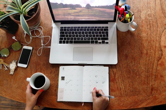 overhead view of schedule planner and laptop on desk
