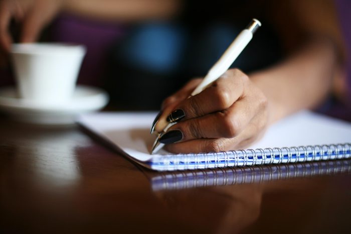 Focus on woman hands writing in notes.