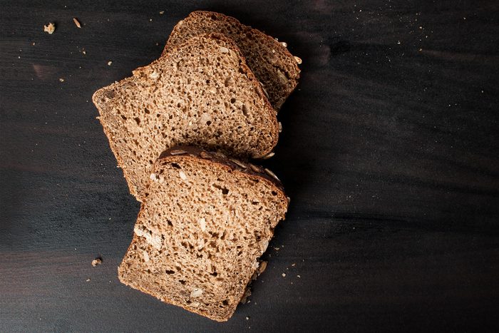 delicious fresh baked slices of bread with sunflower seeds on a dark table photographed from above, horizontal image