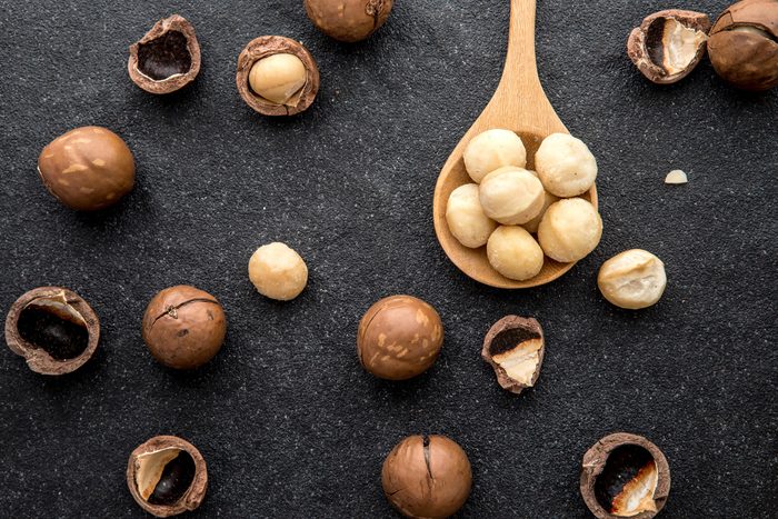 Close up The Macadamia nuts on dark black stone and copy space background , superfood and healthy food concept , overhead or top view shot