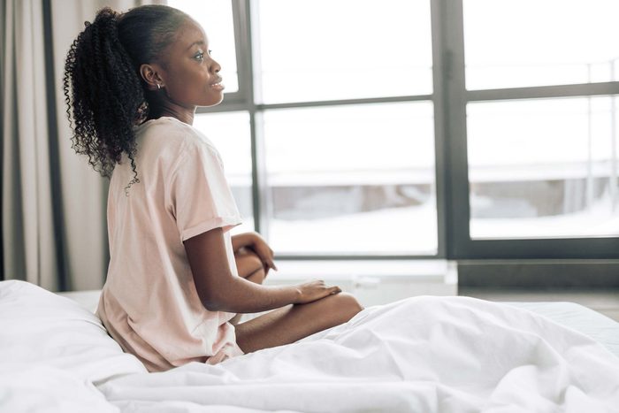 girl bed sitting window thinking