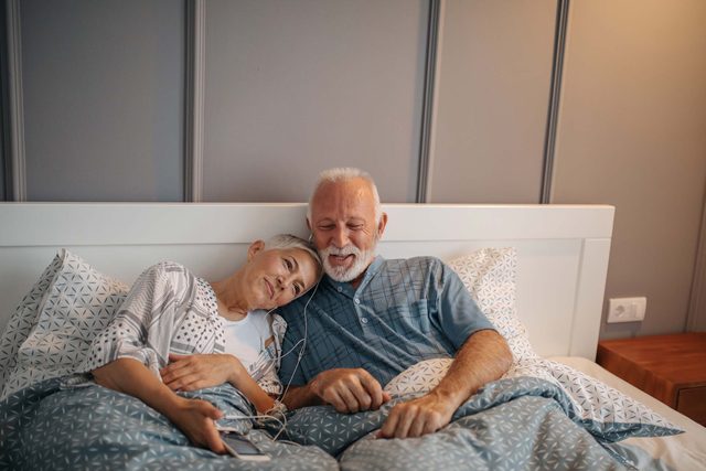man and woman listening to music in bed