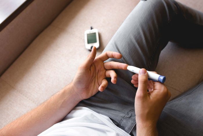 man using a finger-stick glucometer