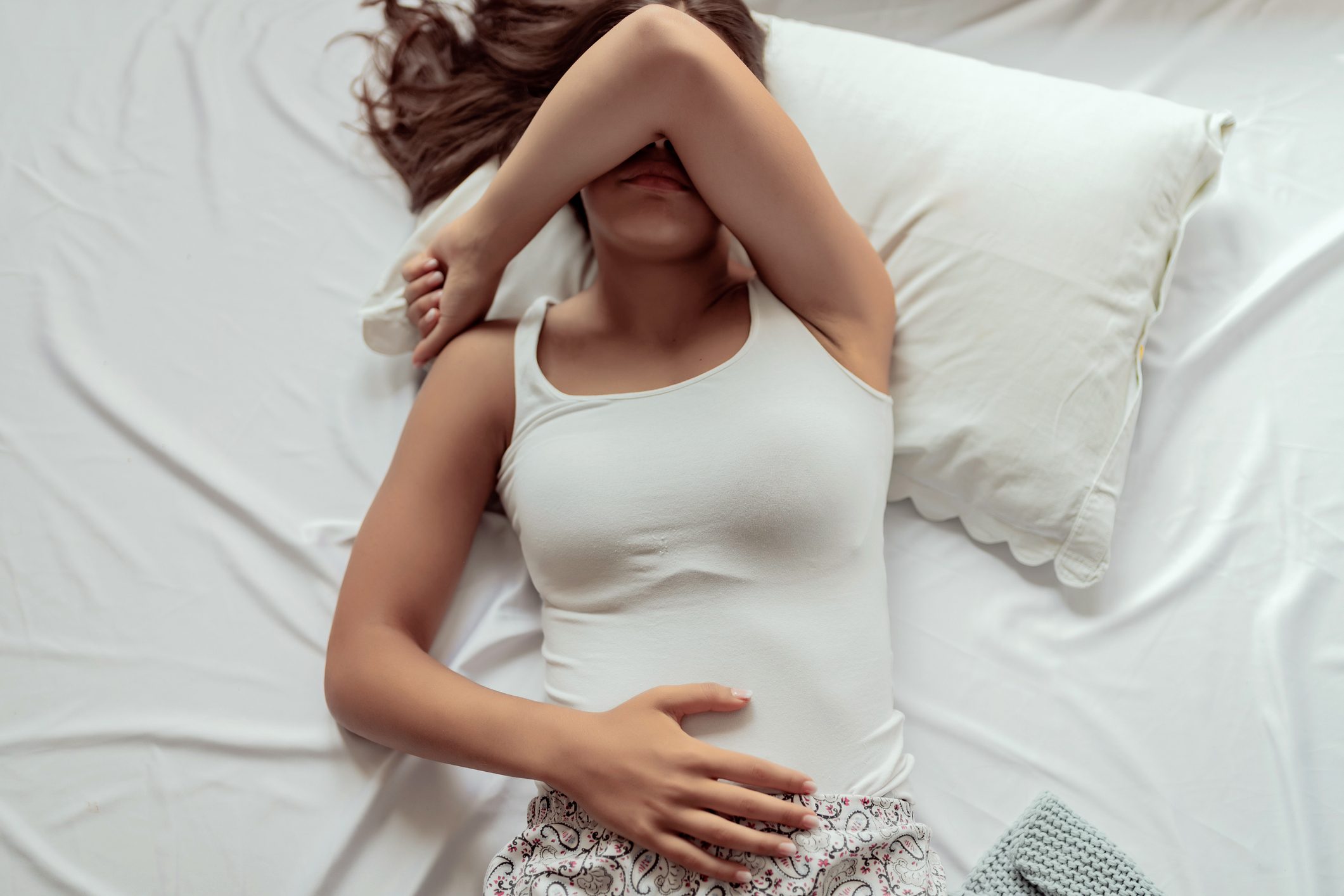 woman in bed with arm over eyes