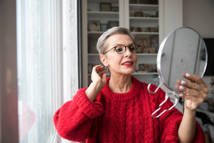 mature woman looking into hand held mirror
