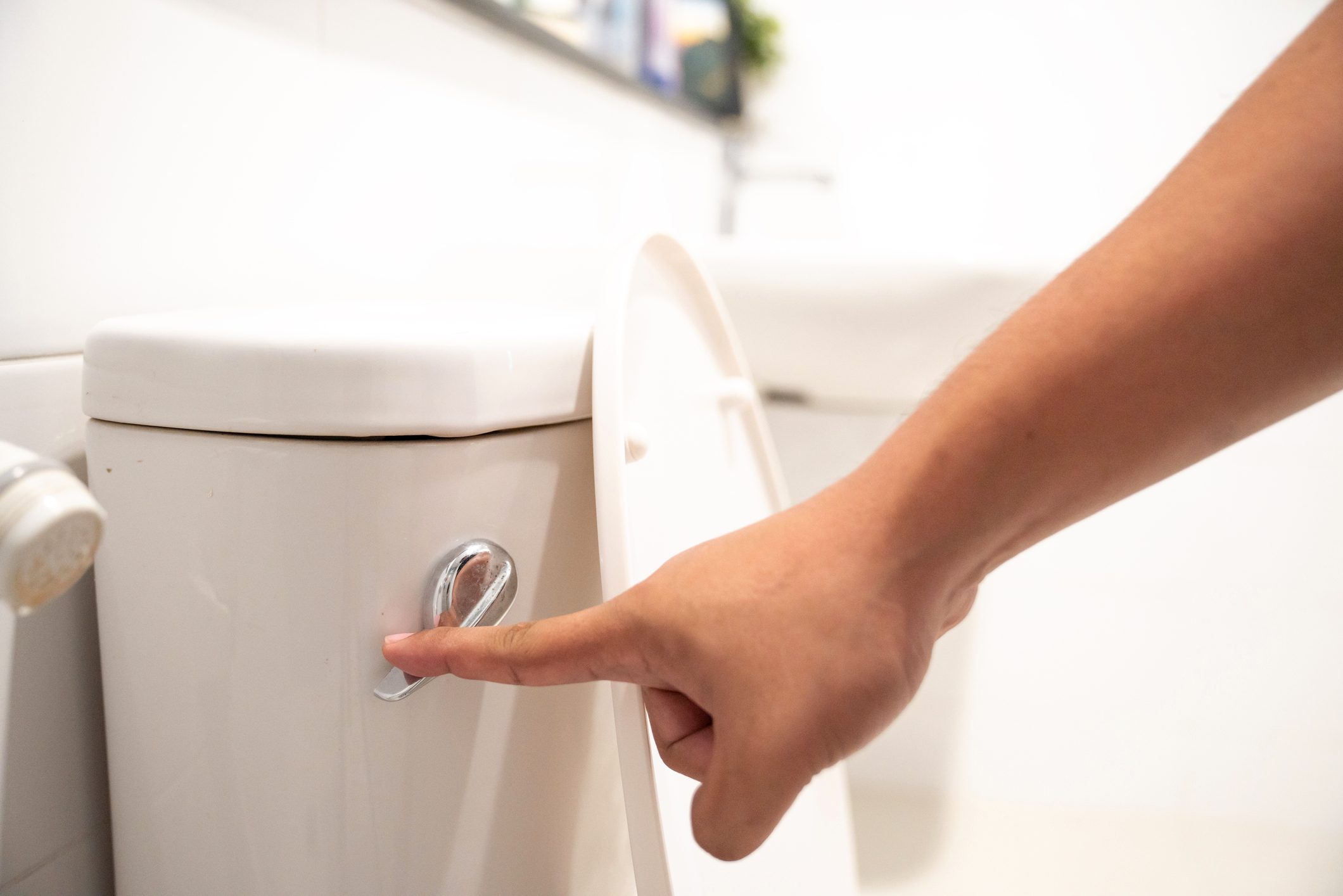 close up of hand flushing toilet