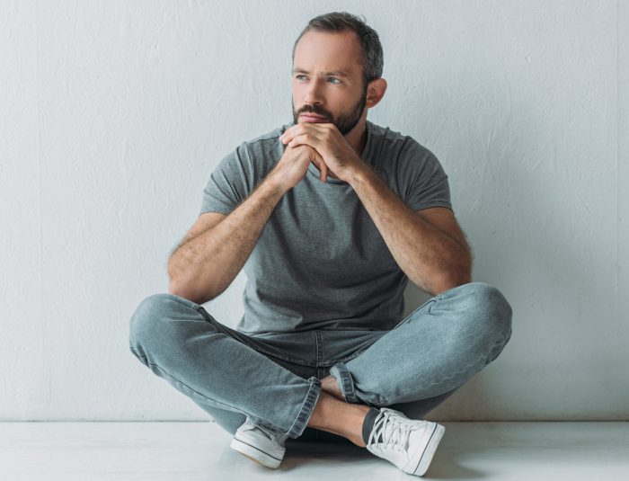 unhappy bearded man sitting in floor and looking away