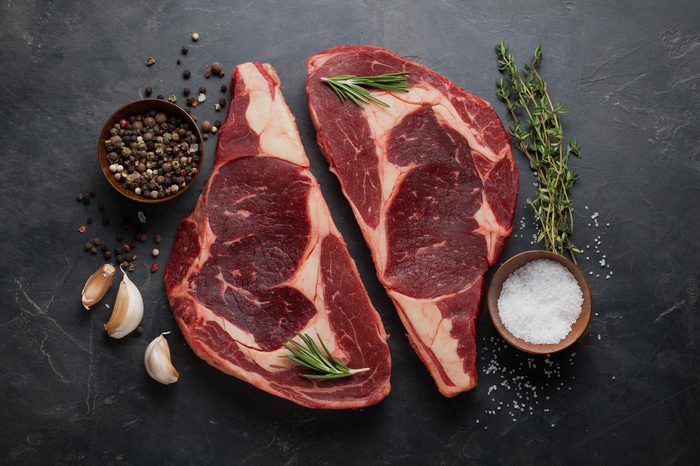 Raw fresh marbled meat Steak Ribeye Black Angus on black marble background. Beef with spices on a dark stone table. Top view