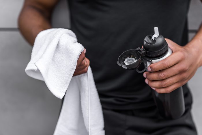 cropped shot of young african american sportsman holding sports bottle and towel