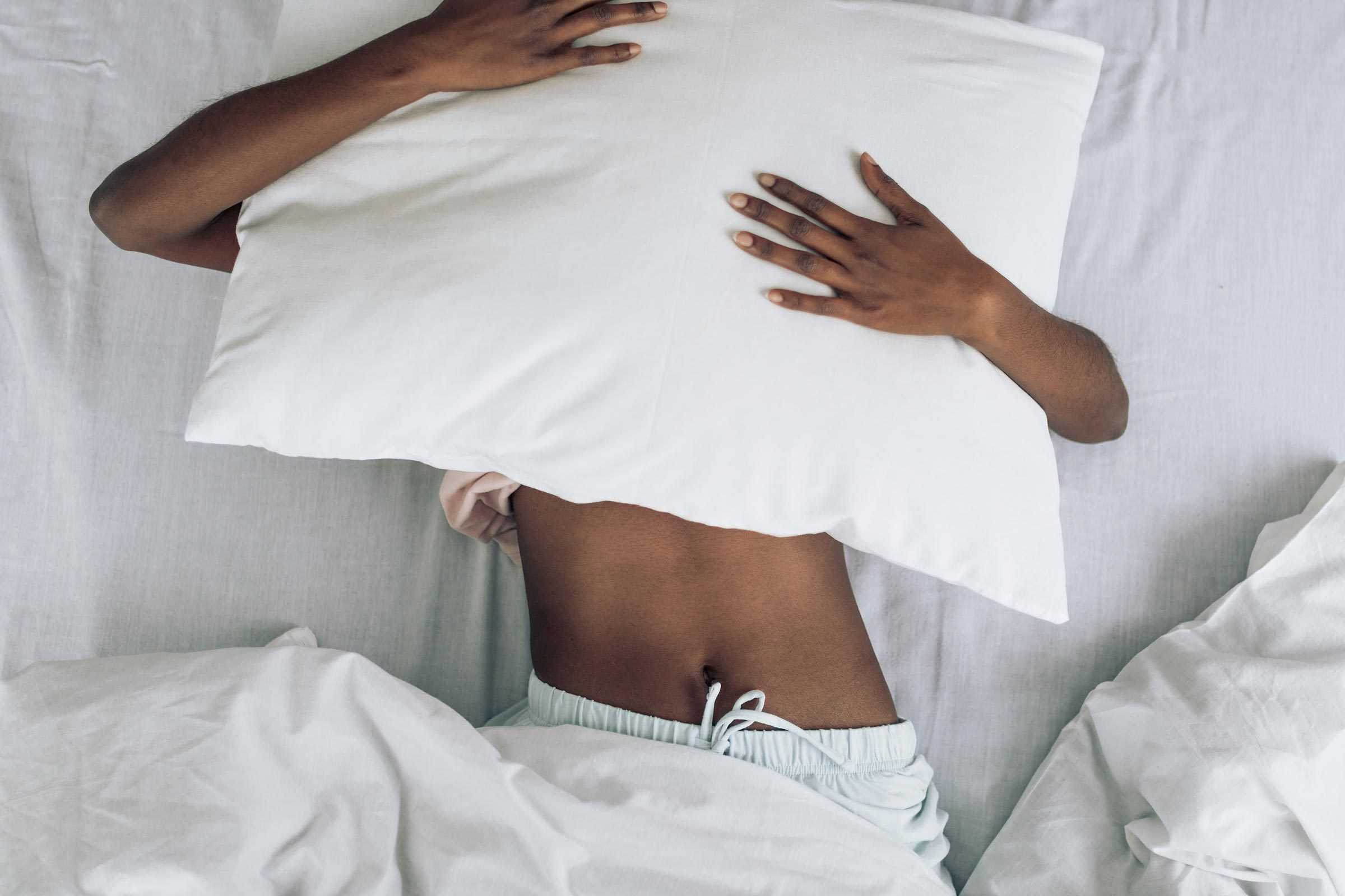 tired woman with pillow over her face