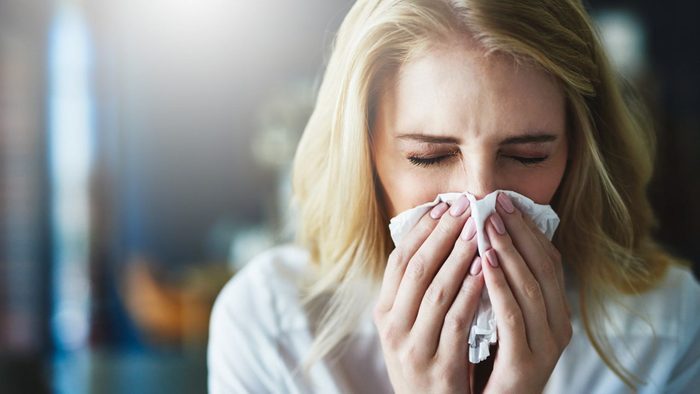 woman sneezing into a tissue