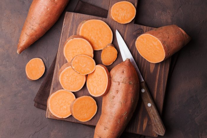 Sweet potato on wooden kitchen board from above.