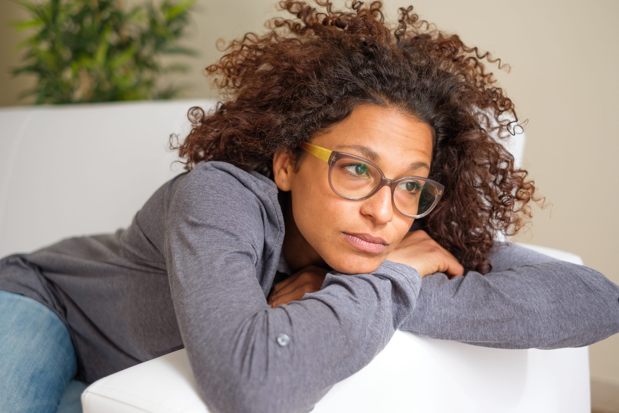 woman laying on couch at home exhausted and worried