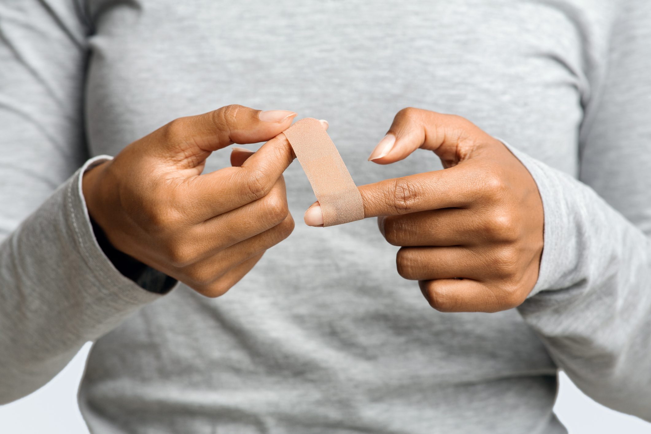 close up of woman putting bandage on finger