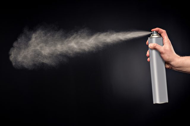 Close-up view of human hand and spray bottle isolated on black