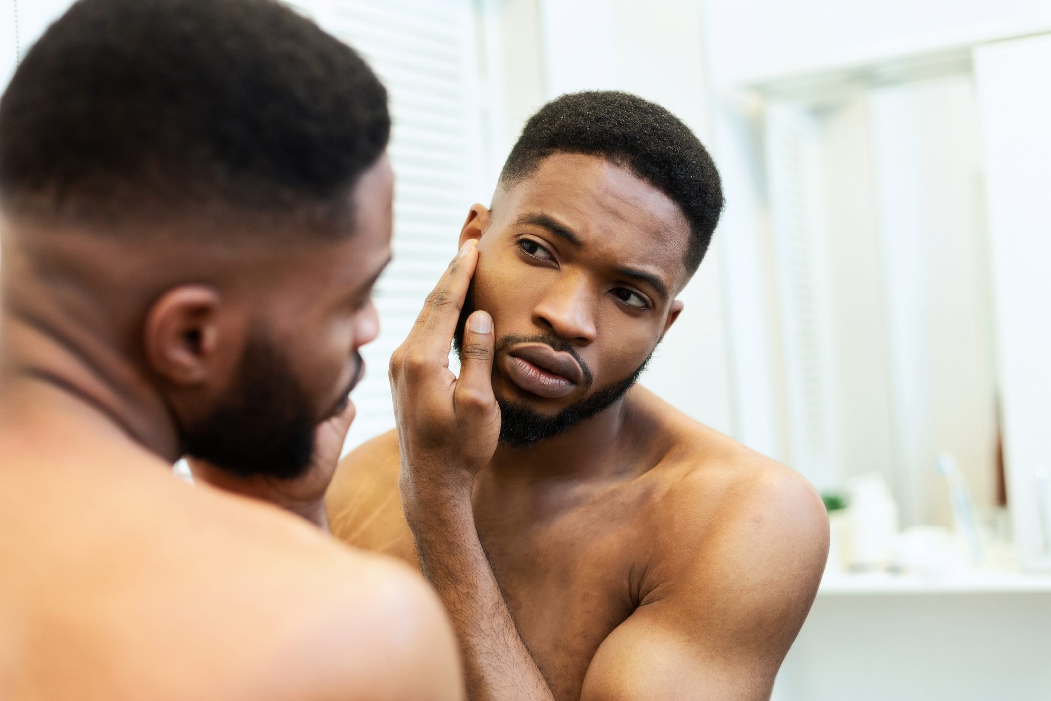 man looking at face in mirror