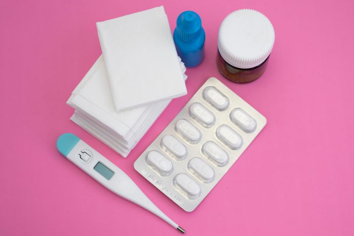 Tissues, nose drops, thermometer, pills and blister on pink background. View from above. Flat lay