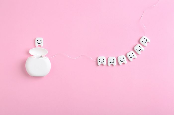 Flat lay composition with small plastic teeth and dental floss on color background