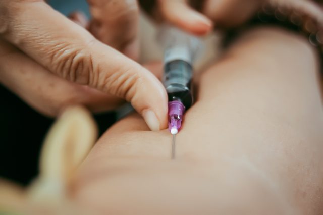 Close up pricking needle syringe in the arm blood sample for blood test.; Shutterstock ID 1096691849