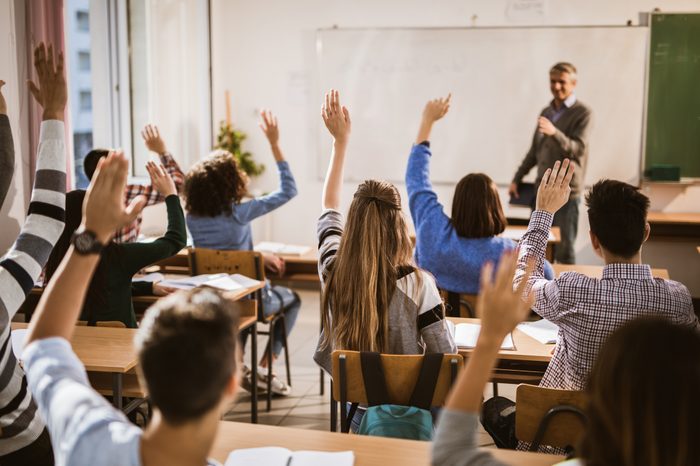 students raising hands in class