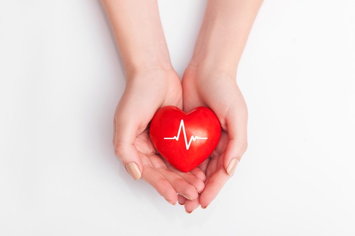 People health concept - close up of woman's cupped hands showing red heart with heart beat.