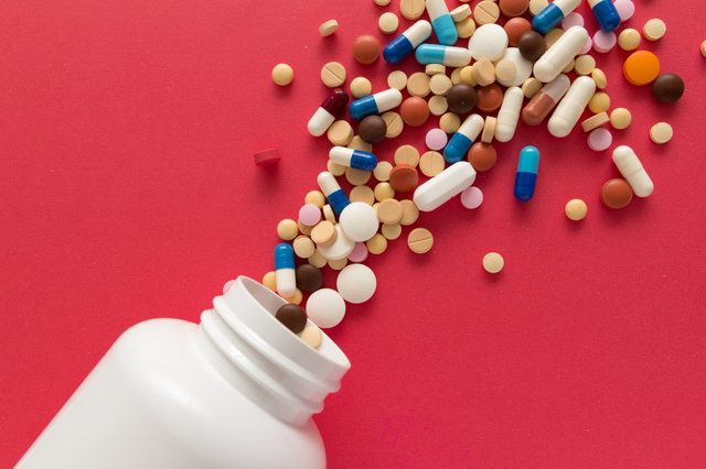 pills and pill bottle on red background