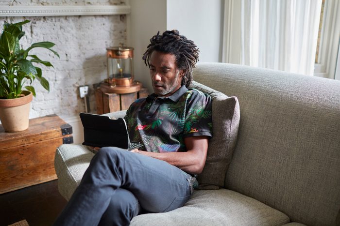 man resting at home using tablet device