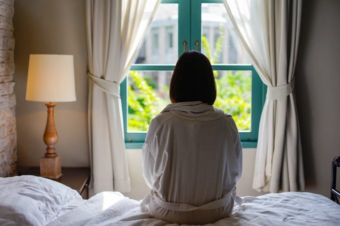 lone woman sitting on edge of bed