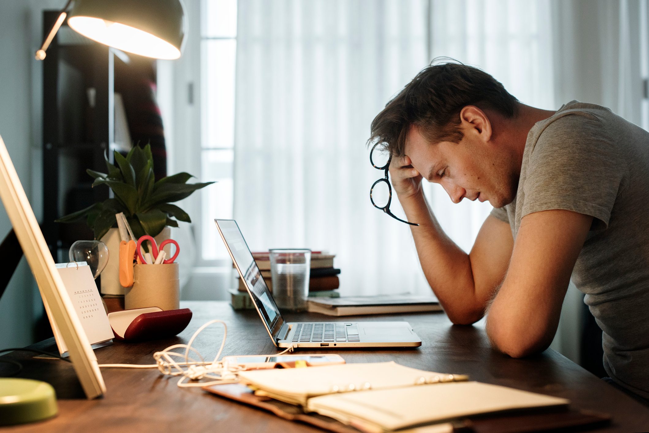 side view of man sitting at desk and struggling with work