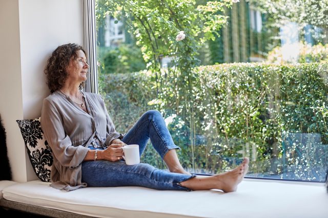 woman sitting on window seat looking out window