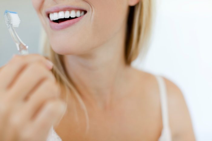 cropped shot of woman brushing teeth