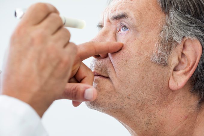 eye doctor examining elderly man's eyes