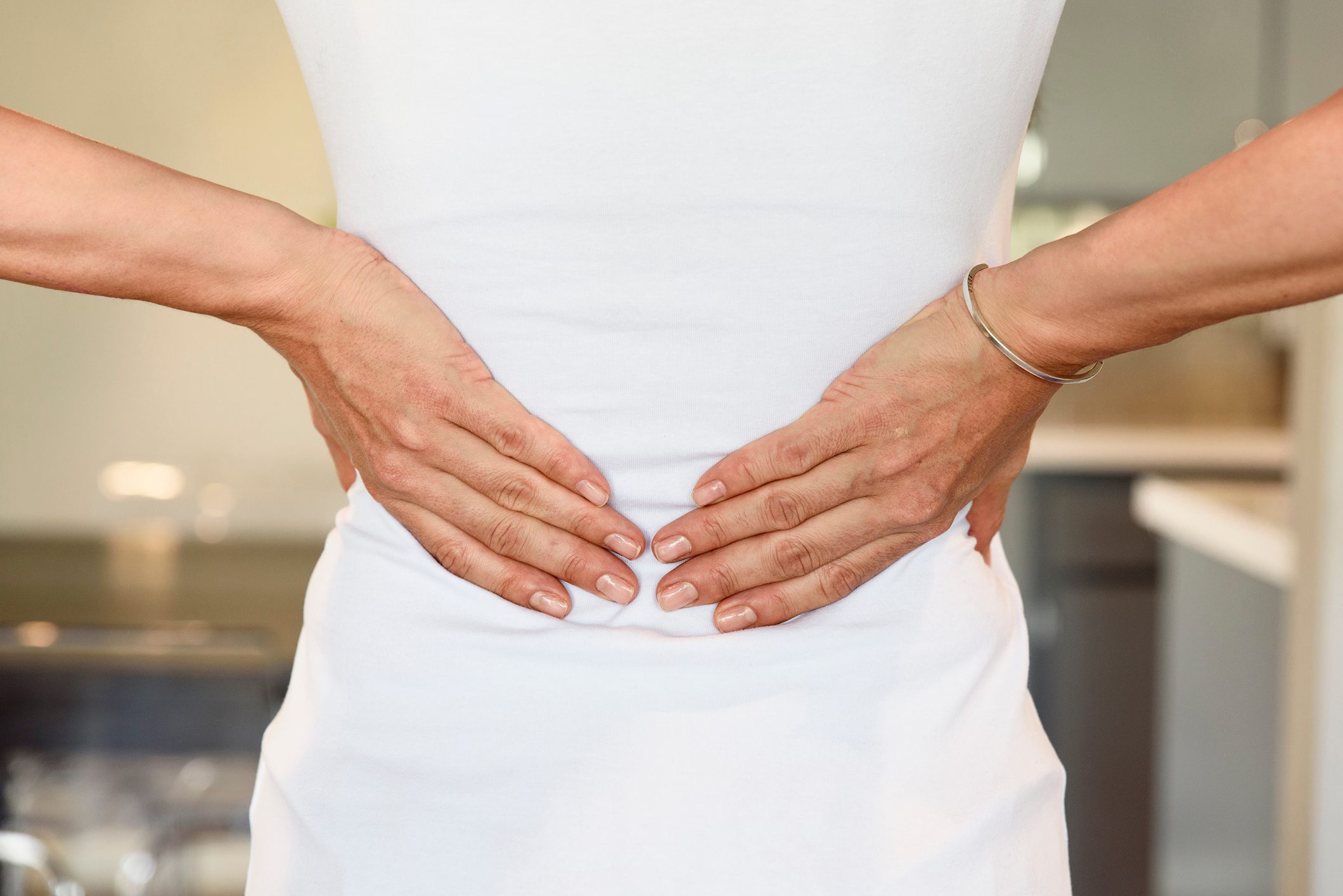 cropped rear shot of woman's hands on lower back