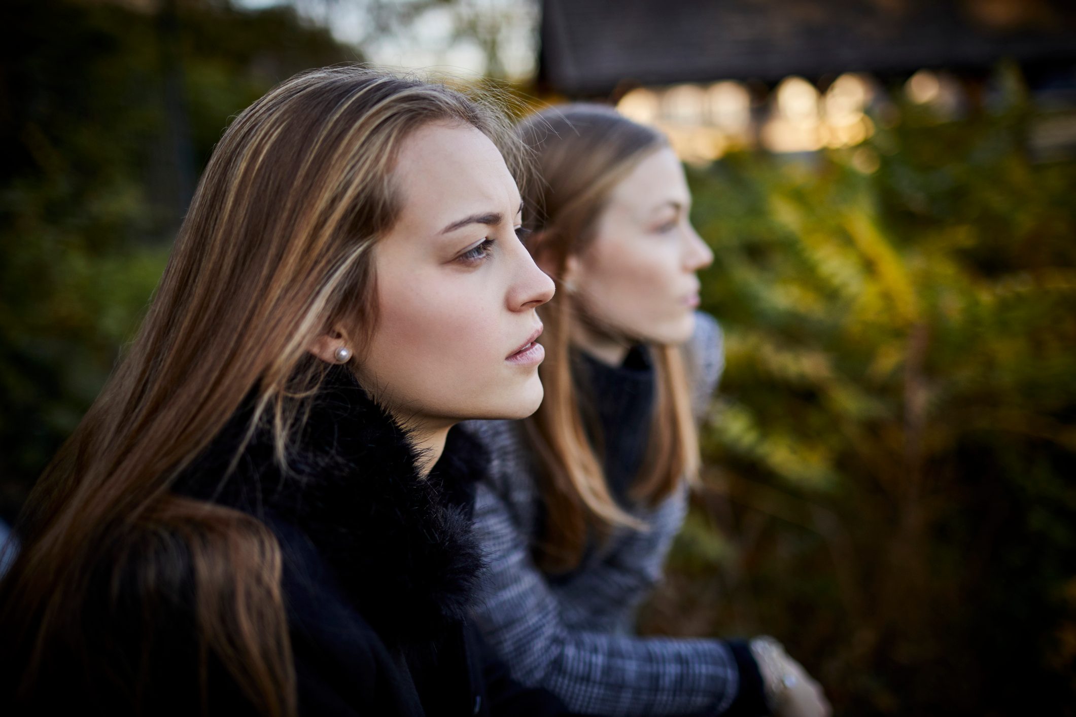 two young women leaning on railing looking at view