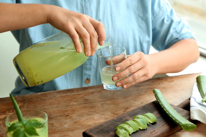 woman pouring aloe vera juice into glass