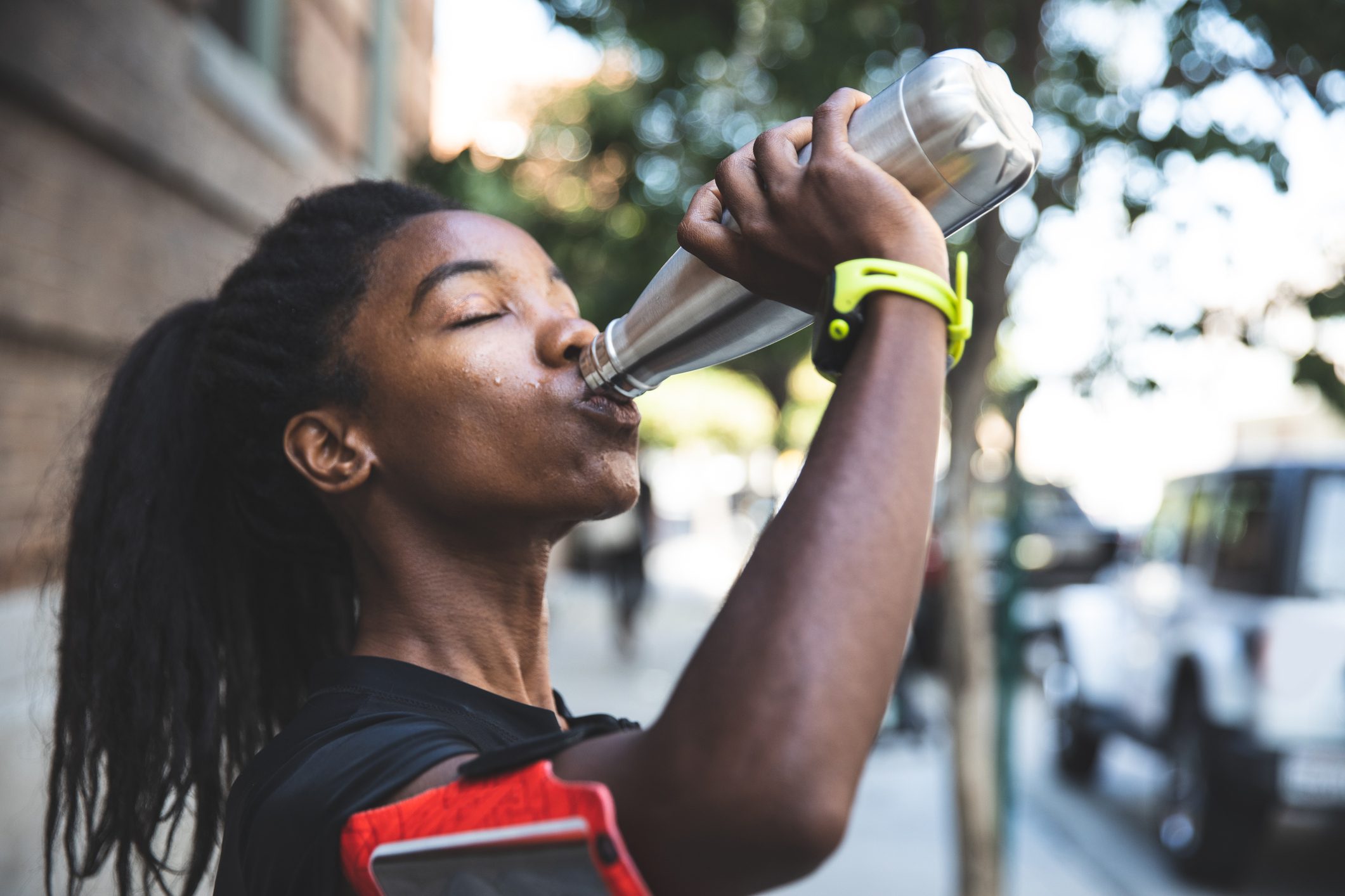 woman drinking out of stainless steel reusable water bottle