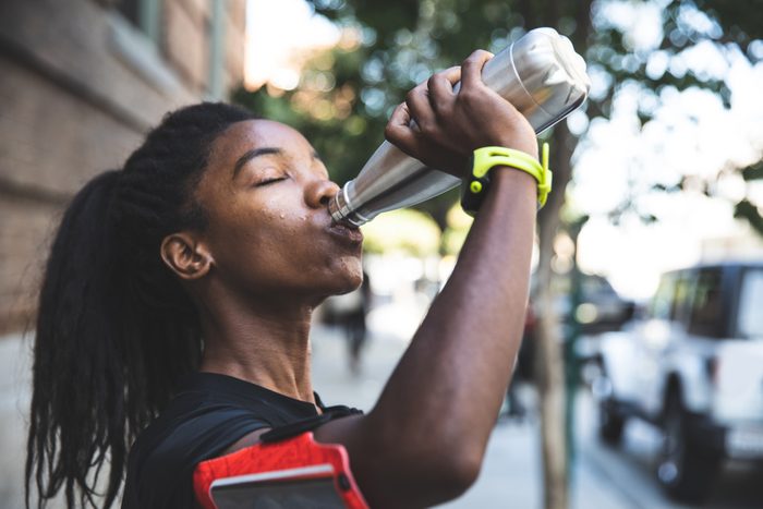woman drinking out of stainless steel reusable water bottle