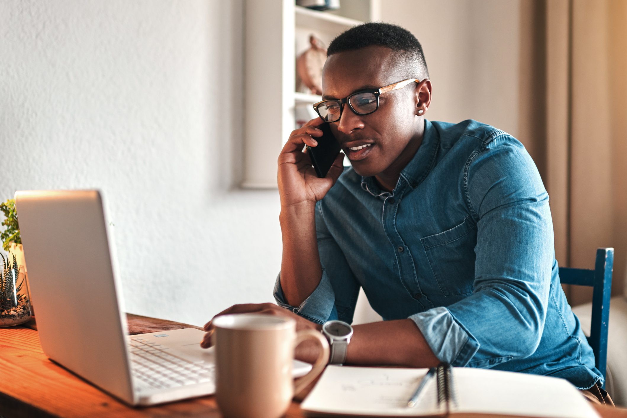 man working at home while talking on the phone