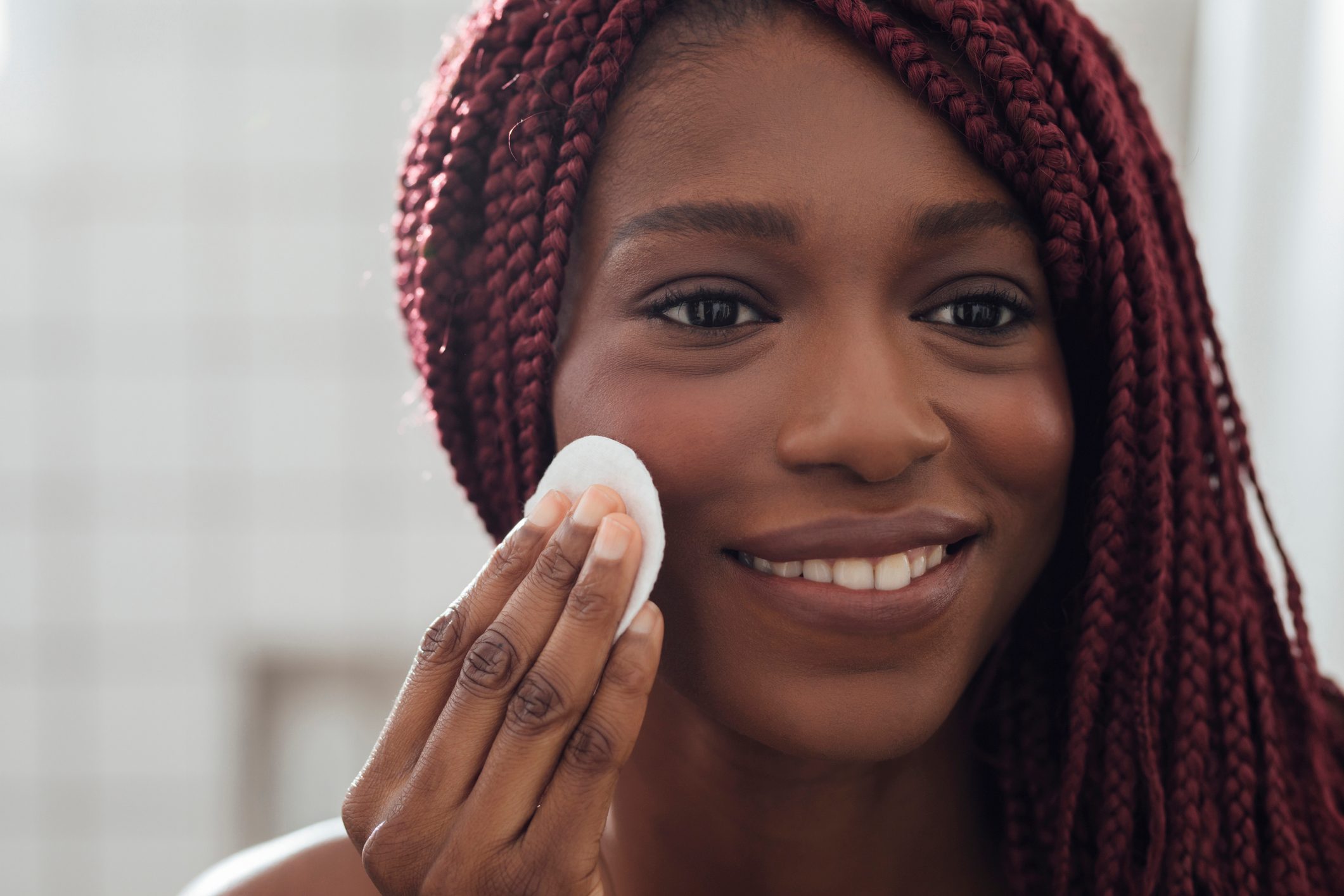 woman cleaning her face with cotton pad