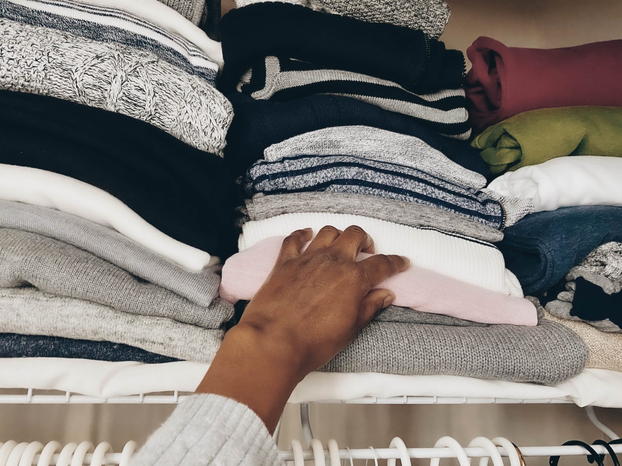 woman grabbing sweater from closet