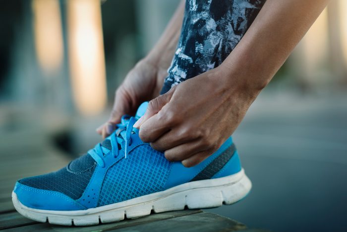 close up of woman tying sneakers before workout