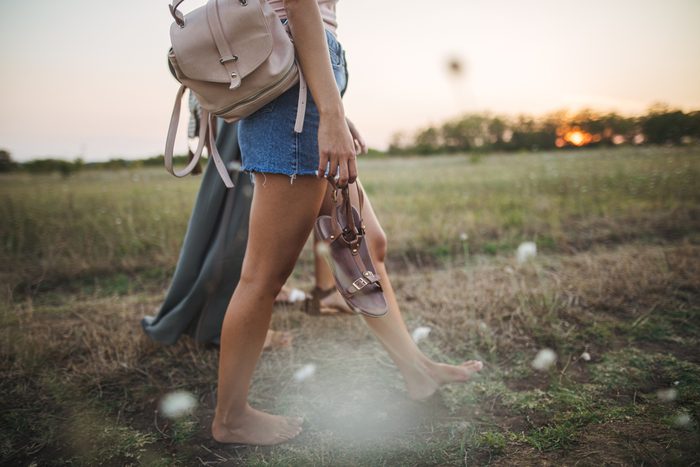 couple walking barefoot through field