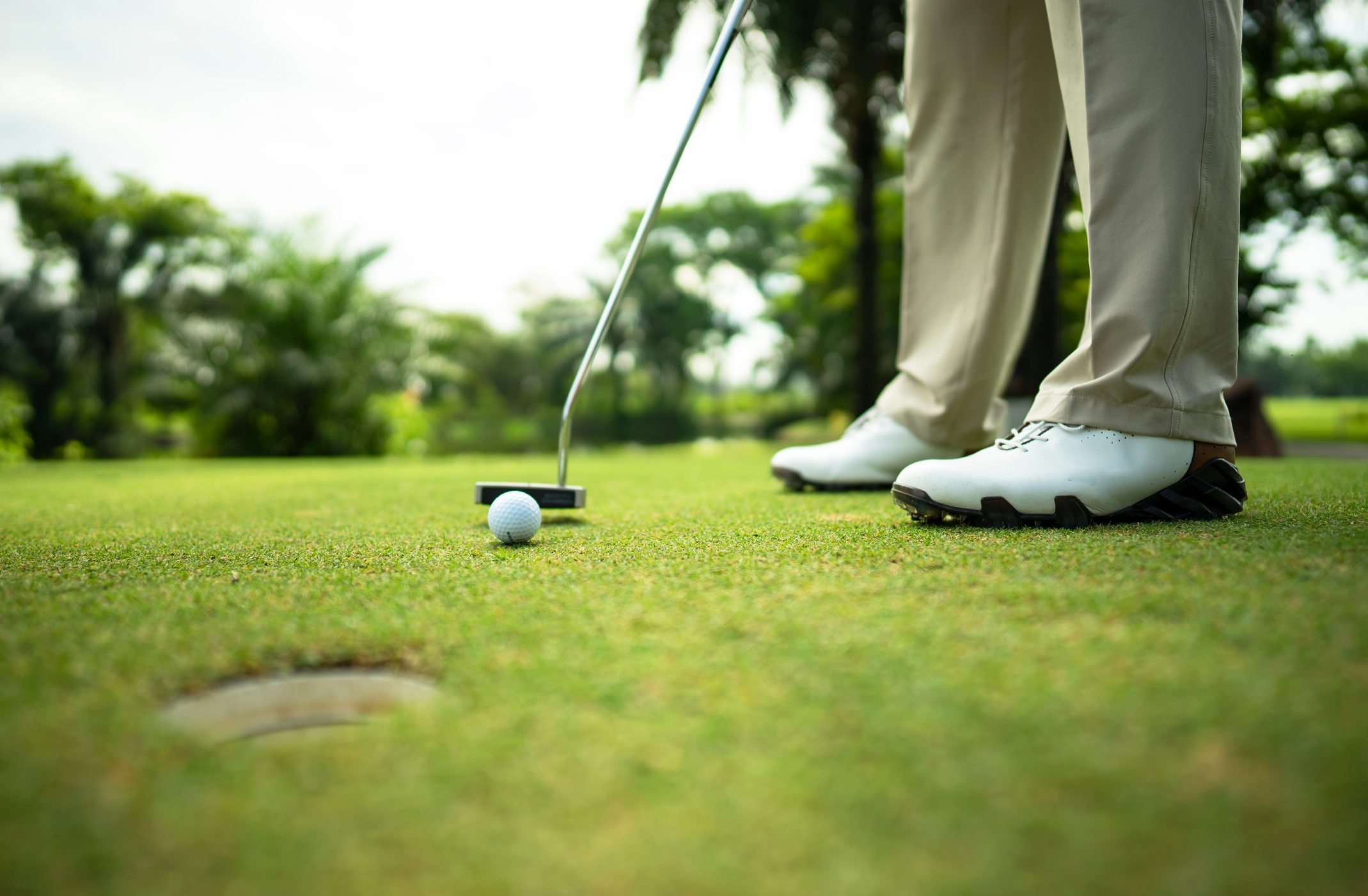 cropped shot of lower half of golfer putting on green