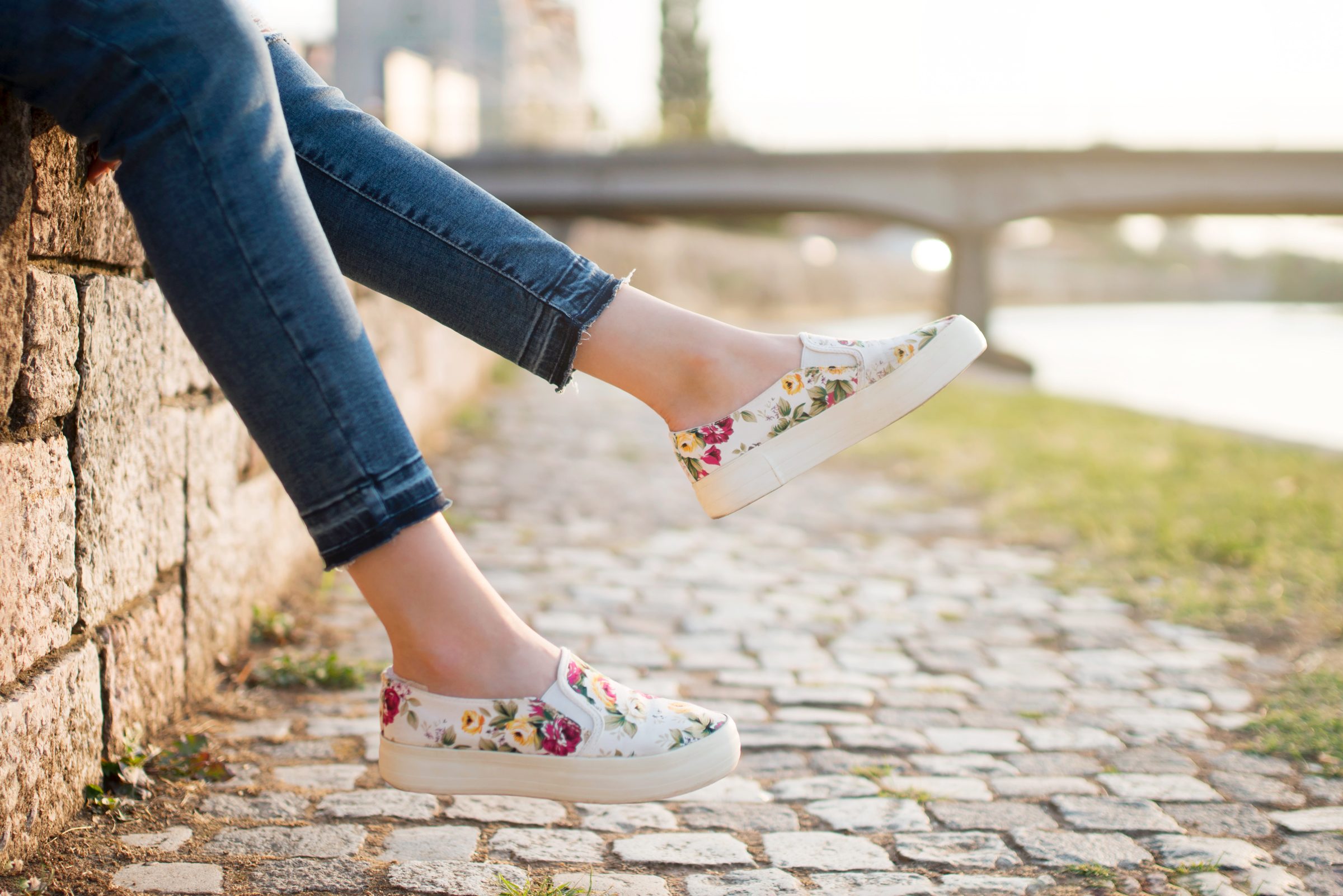 woman sitting on a wall wearing Floral slip on sneaker