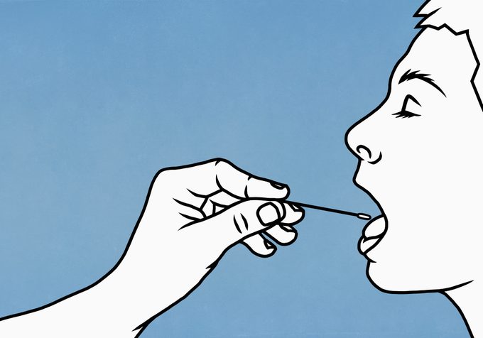 hand of nurse swabbing inside of patient's mouth for test