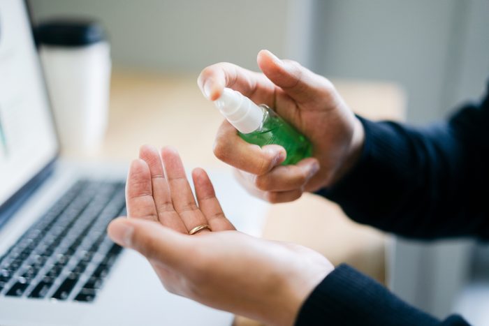close up of man using hand sanitizer spray