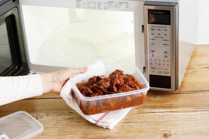 woman heating leftovers in microwave